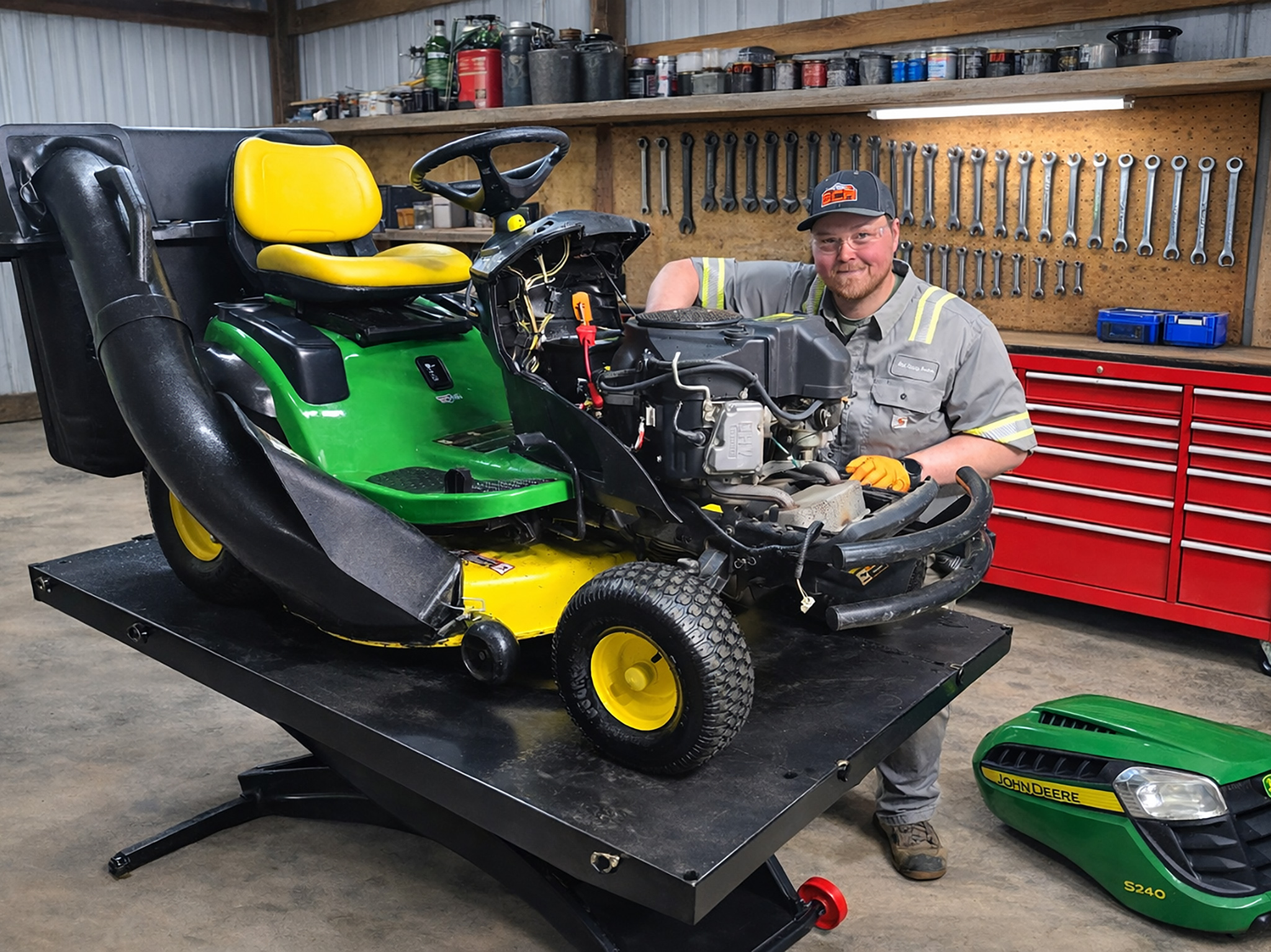 Technician working on the engine of a John Deere riding mower